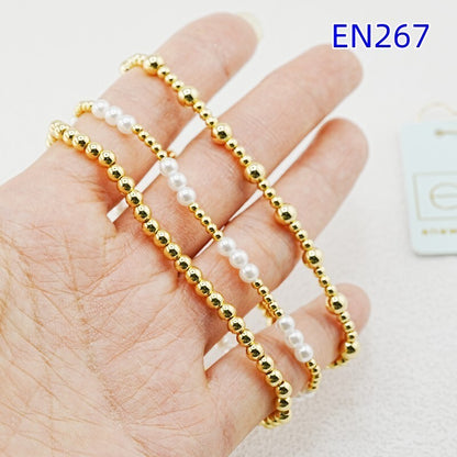 Three gold beaded bracelets with white pearl beads on a hand
