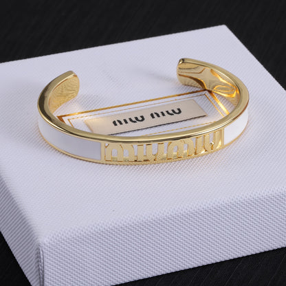 White enamel openwork logo bangle with gold-tone cuff and cutout lettering