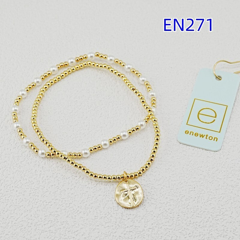 Two gold-tone bead bracelets with white pearls and round disc cross pendant charm