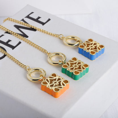 Gold-tone chain necklace with enamel square cutout logo charms in orange, green, and blue