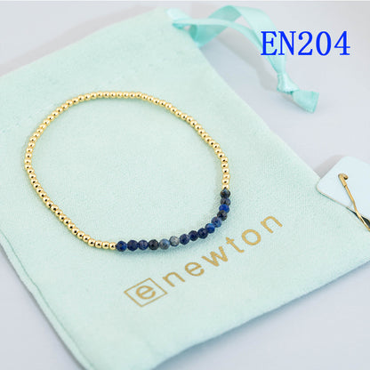 Elastic beaded bracelet with gold round beads and a deep blue bead accent row.