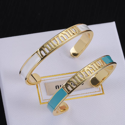 Enamel openwork logo bangle with gold-tone frame and white enamel, teal accent