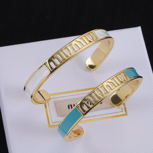 Enamel openwork logo bangle with gold-tone frame and white enamel, teal accent