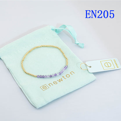 Elastic beaded bracelet with gold round beads and dark blue faceted bead details.
