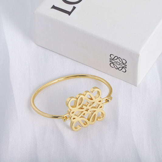 Gold open cuff bracelet with polished square cutout logo detail