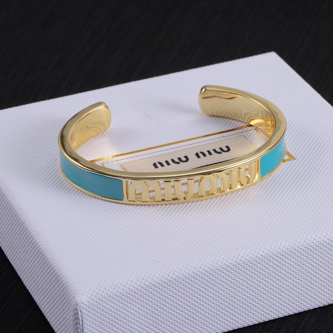 Teal enamel openwork logo bangle with gold-tone cuff and white enamel sections