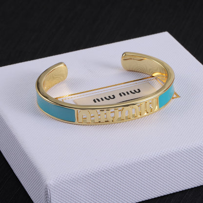 Teal enamel openwork logo bangle with gold-tone cuff and white enamel sections