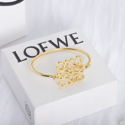 Gold polished open cuff bracelet with cutout logo detail and small hook closure