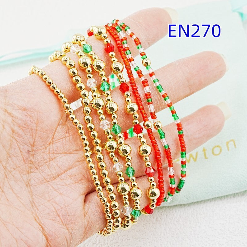 Beaded bracelet set: red and green beads with gold-tone ball accents, shown on hand