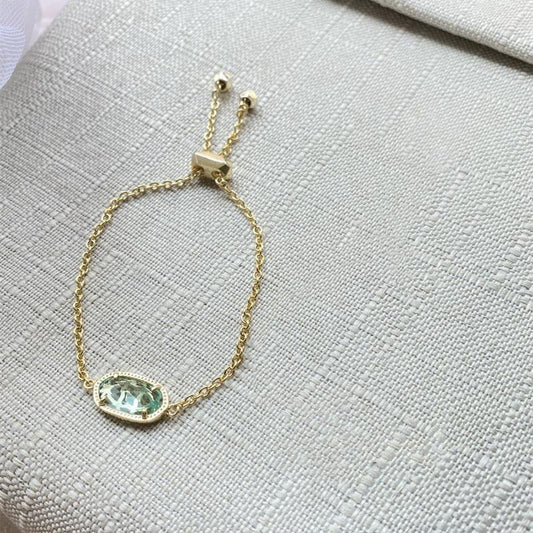 Gold-tone chain bracelet with oval aqua gemstone pendant and small square clasp links