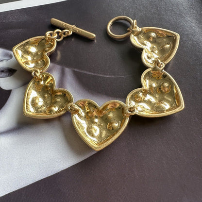 Gold-tone heart charm bracelet with openwork heart links and toggle bar clasp
