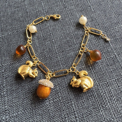 Gold-tone charm bracelet with squirrel, acorn, and pearl beads on link chain