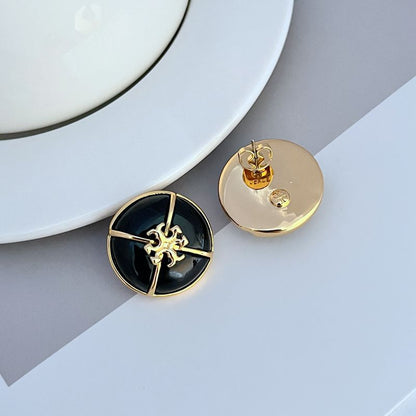 Tory Burch black enamel button stud earrings with gold-tone emblem; shows one disc back