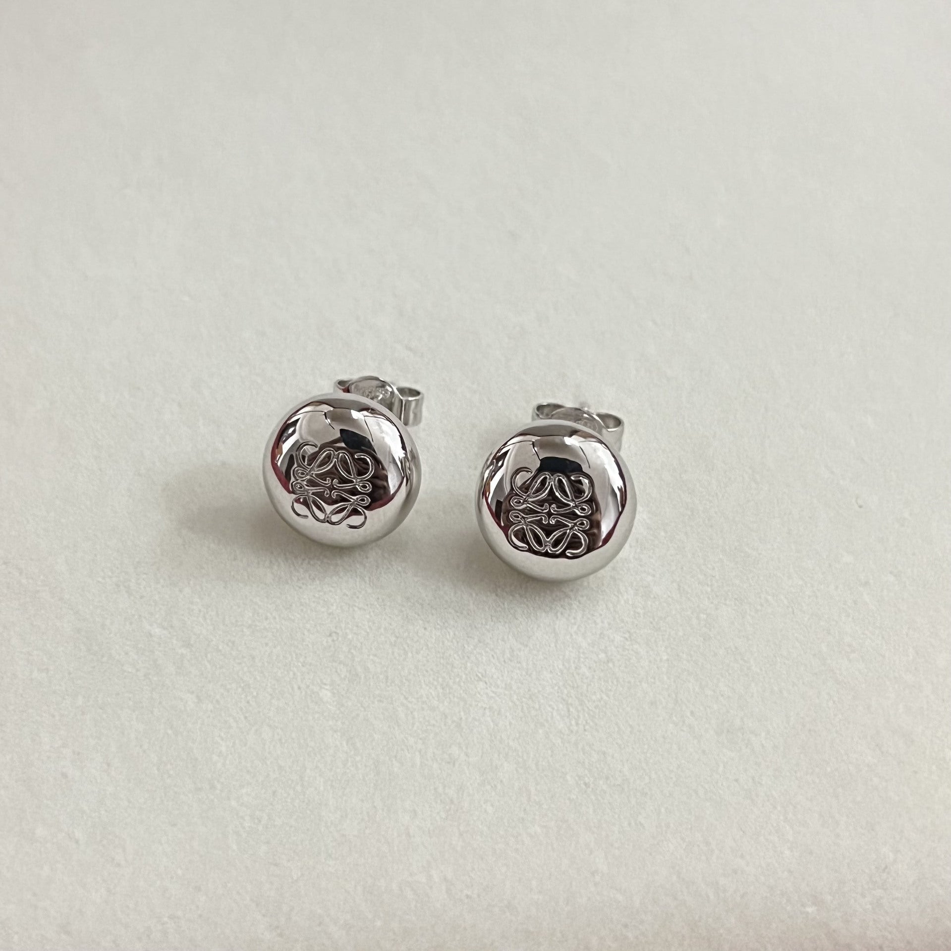 Silver round stud earrings with smooth bean shape and engraved knot design, stud backs