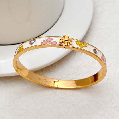 Gold-tone enamel flower and paw motif bangle with hinged clasp