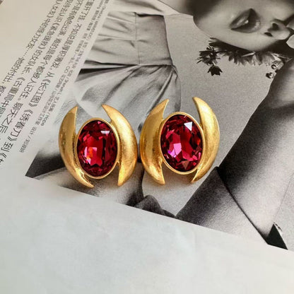 Gold-tone oval crystal stud earrings with deep red faceted stones