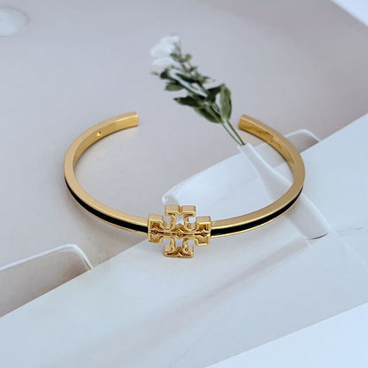 Open gold-tone metal bangle with cutout logo charm and dark enamel edge