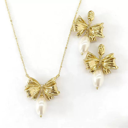 Gold bow pendant necklace with pearl drop and matching gold-tone bow stud earrings