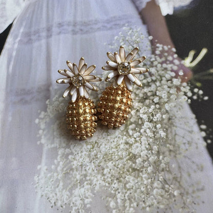 Enamel flower and pineapple diamond earrings with off-white flower tops and gold textured drops.