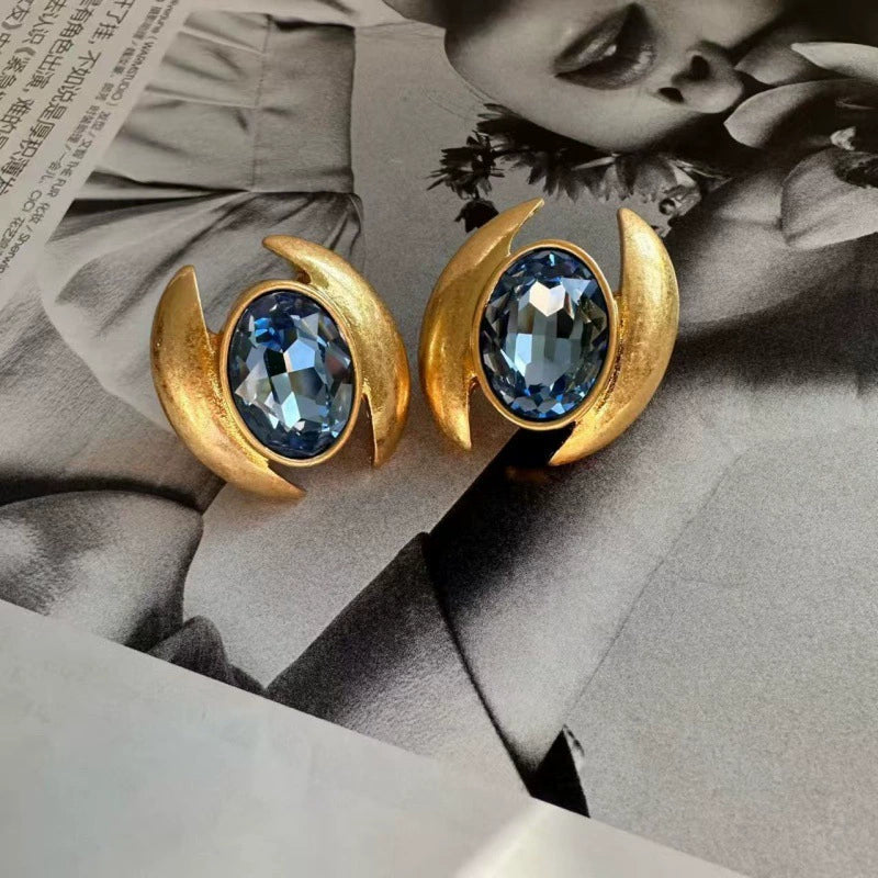 Oval crystal stud earrings with light blue gem in gold-tone crescent frame