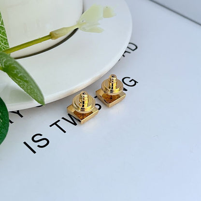 Gold-tone square logo stud earrings with visible hinge and post detail