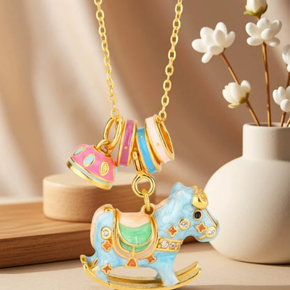 Enamel-painted rocking horse necklace with blue horse charm and striped bell accent on gold chain