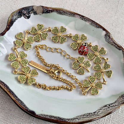 Gold-tone clover crystal necklace with ladybug bead, shown on jewelry dish
