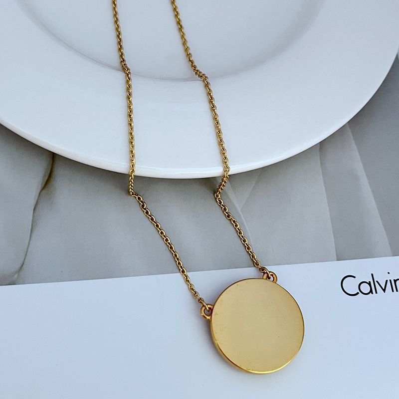 Gold-tone circle coin pendant necklace with dark blue round enamel charm and chain links