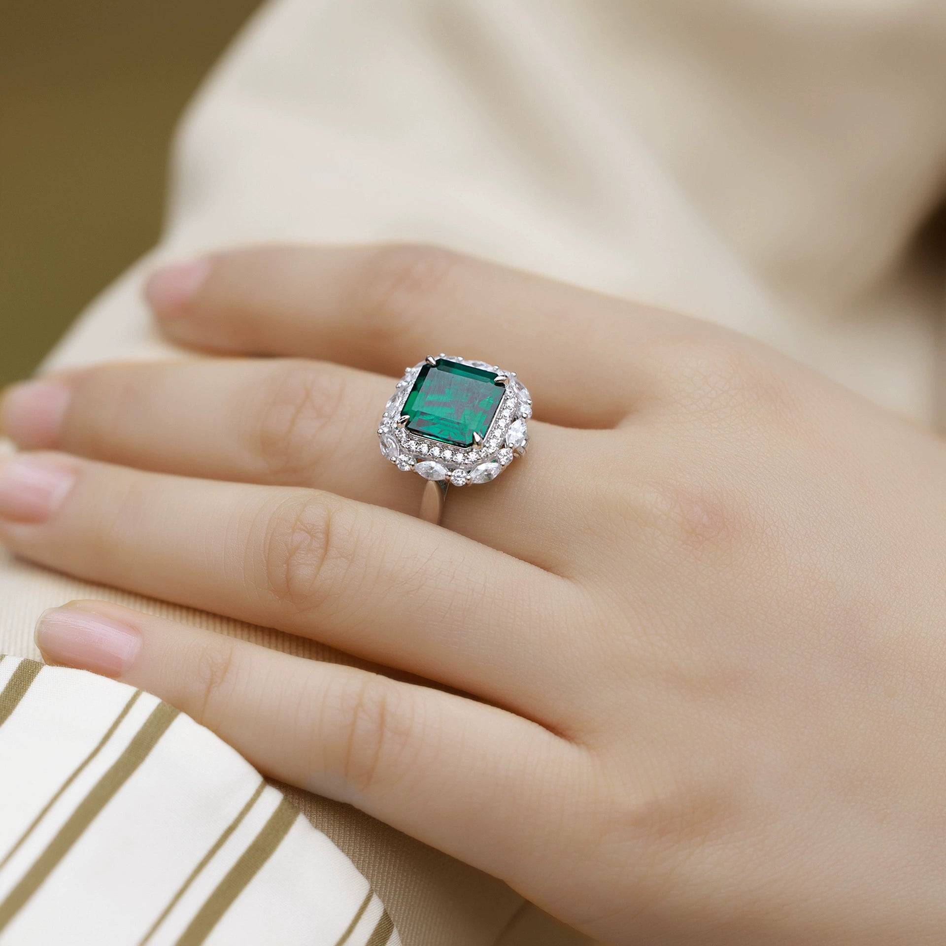Sterling silver green emerald ring with halo stones, worn on hand