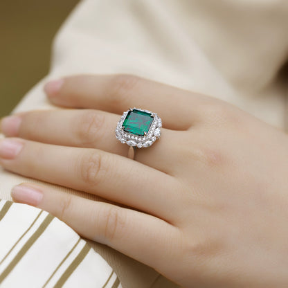 Sterling silver green emerald ring with halo stones, worn on hand