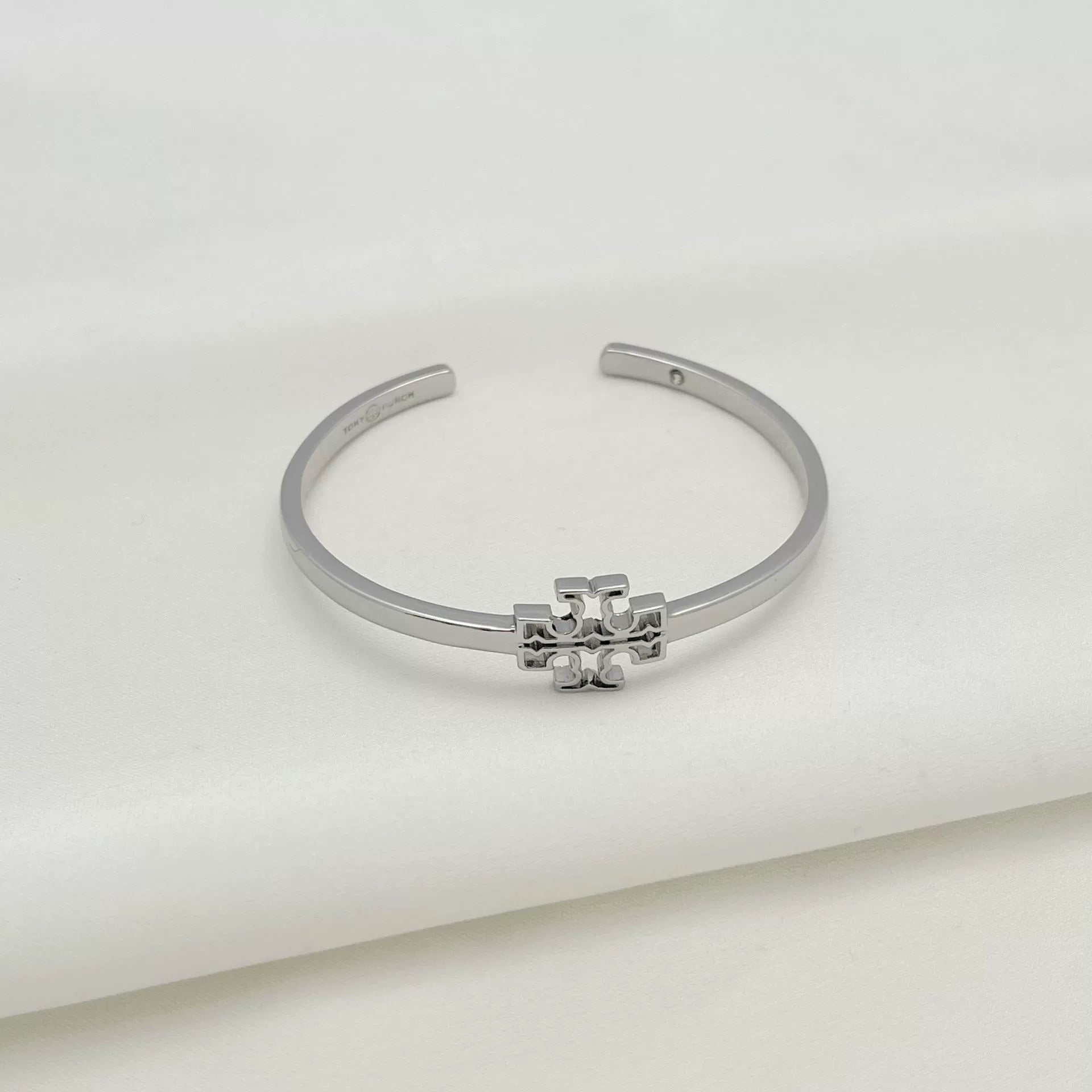 Openwork square logo smooth metal bangle, silver tone with central emblem detail