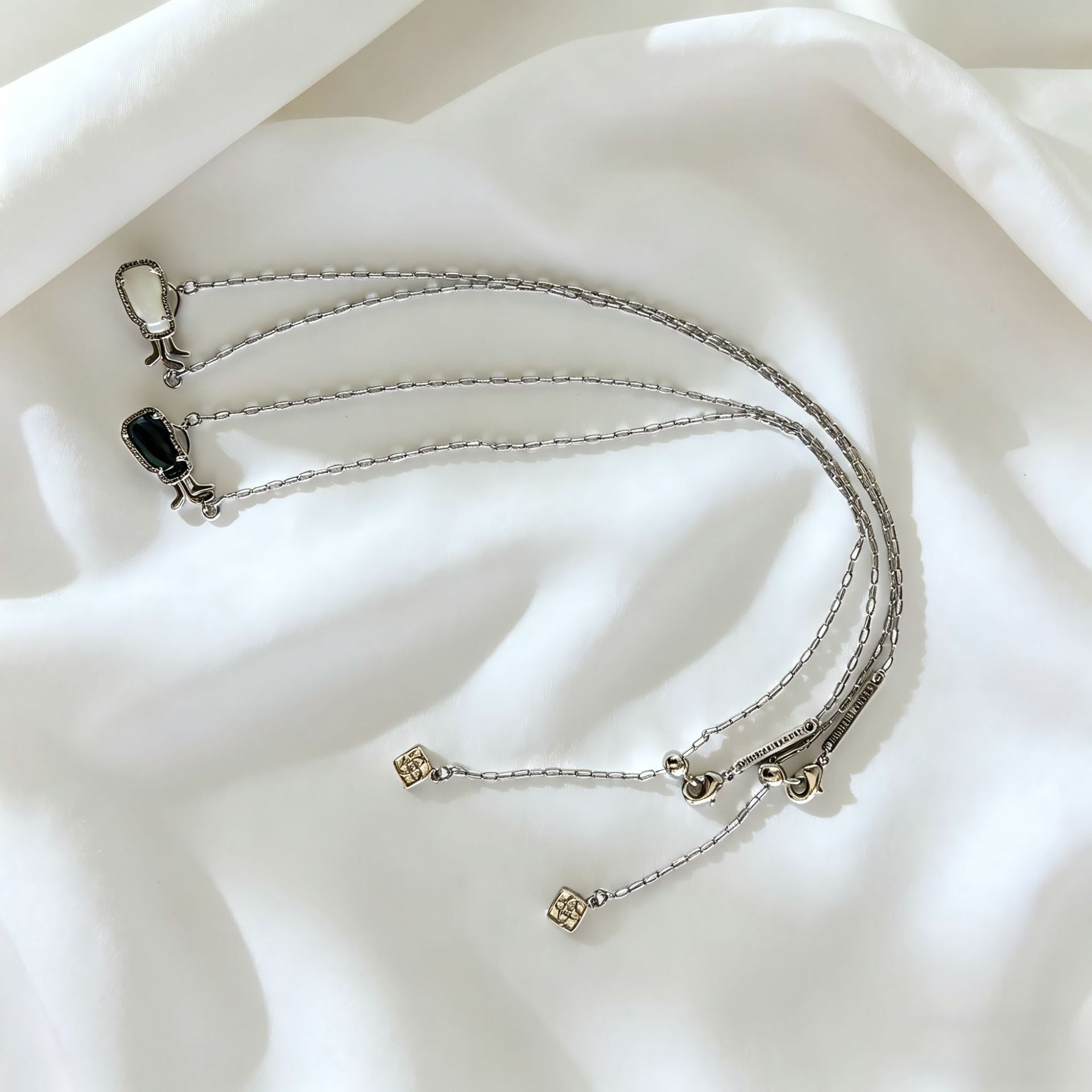 Silver-tone layered charm necklace with thin chains and small square charm pendants