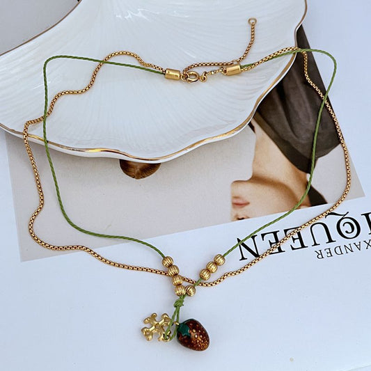 Gold-tone double necklace with red enamel berry pendant and green bead details