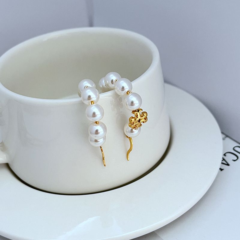 White pearl hoop earrings with gold-tone hook and ornamental charm on bead strand