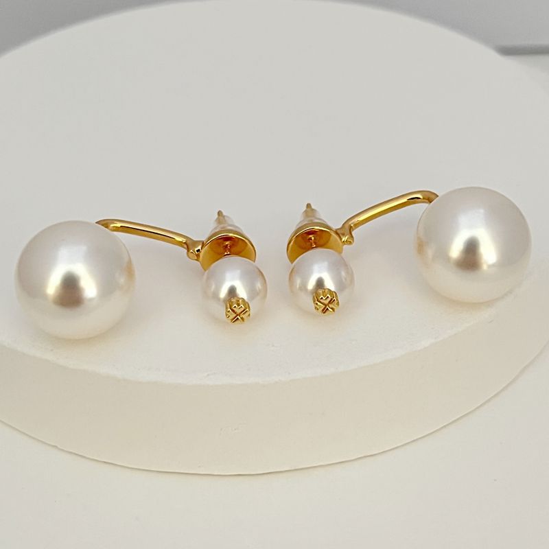 Gold-tone pearl earrings with large and small white pearls on hook
