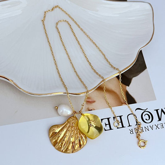 Gold-tone necklace with pearl drop and gold shell-shaped pendant with yellow acrylic piece.