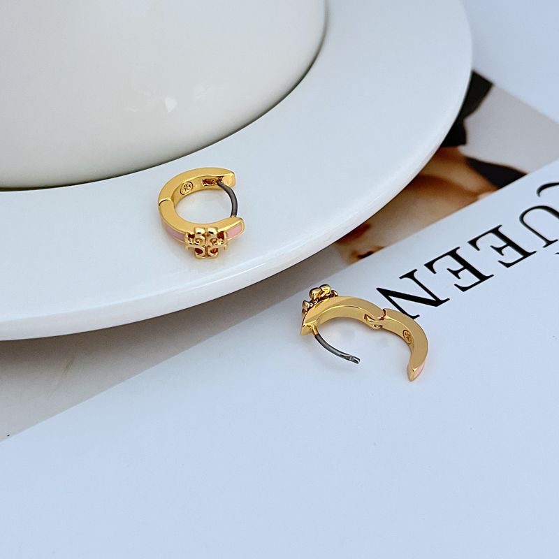 Geometric hoop earrings in gold with pink enamel, close-up of hinge clasp