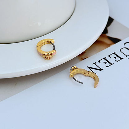 Geometric hoop earrings in gold with pink enamel, close-up of hinge clasp