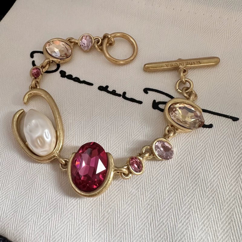 Gold-tone crystal and pearl O-ring bracelet with red marquise center and pink accents