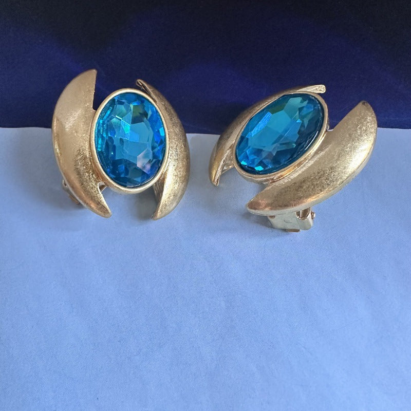 Oval crystal stud earrings with blue gem in gold-tone crescent setting
