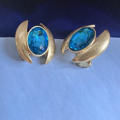 Oval crystal stud earrings with blue gem in gold-tone crescent setting