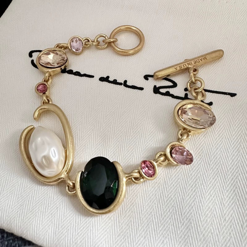 Gold-tone crystal and pearl O-ring bracelet with black oval center stone and pink accents