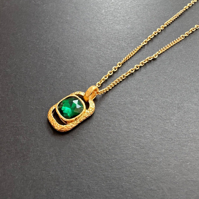 Gold-tone hammered square pendant necklace with green faceted gemstone on chain