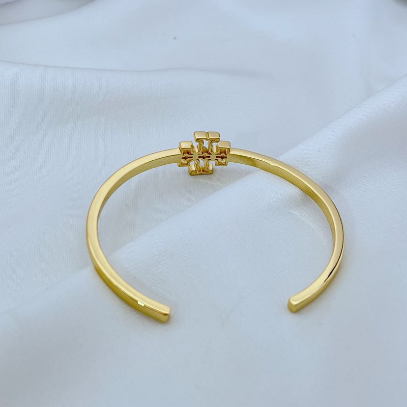 Gold tone open metal cuff bangle with square logo emblem at center