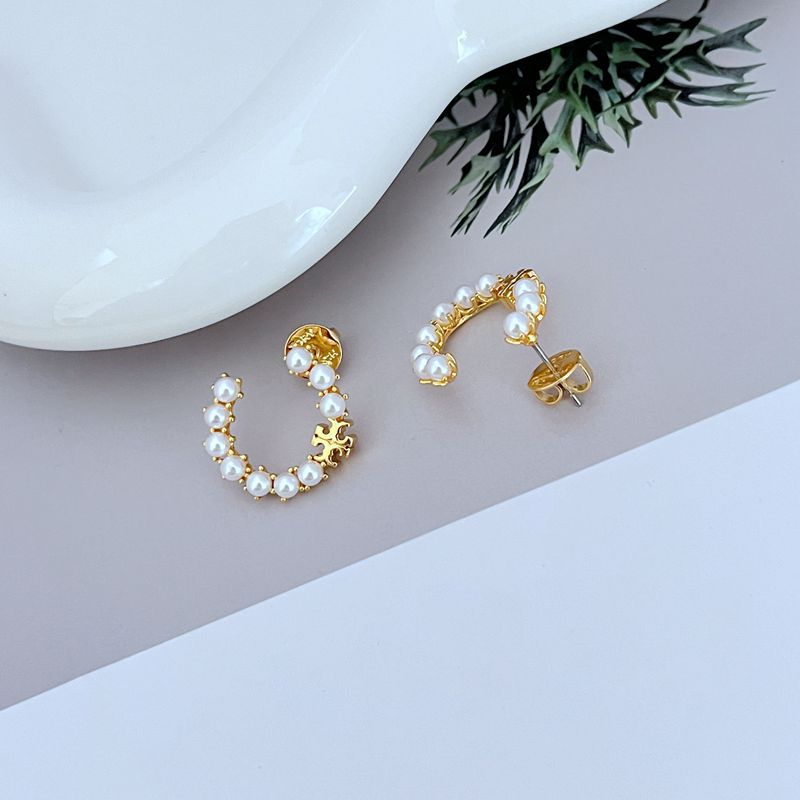 Gold C-shaped earrings with white pearl trim and visible stud posts