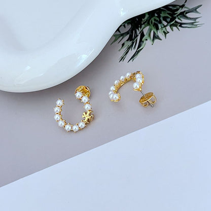 Gold C-shaped earrings with white pearl trim and visible stud posts