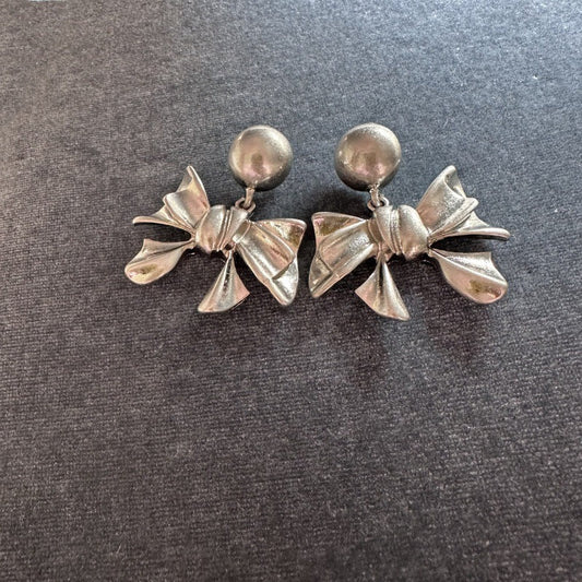 Silver-tone vintage metal bow stud earrings with round ball tops and sculpted bow drops.