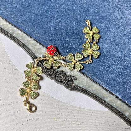 Ladybug and clover charm bracelet with gold-toned chain and green glitter clovers