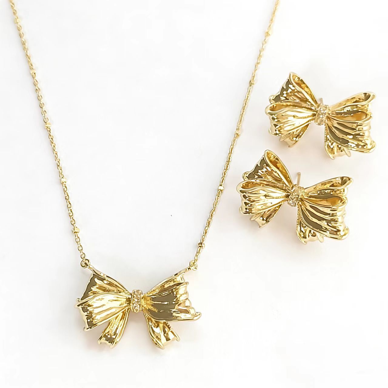 Gold bow stud earrings and matching bow pendant necklace