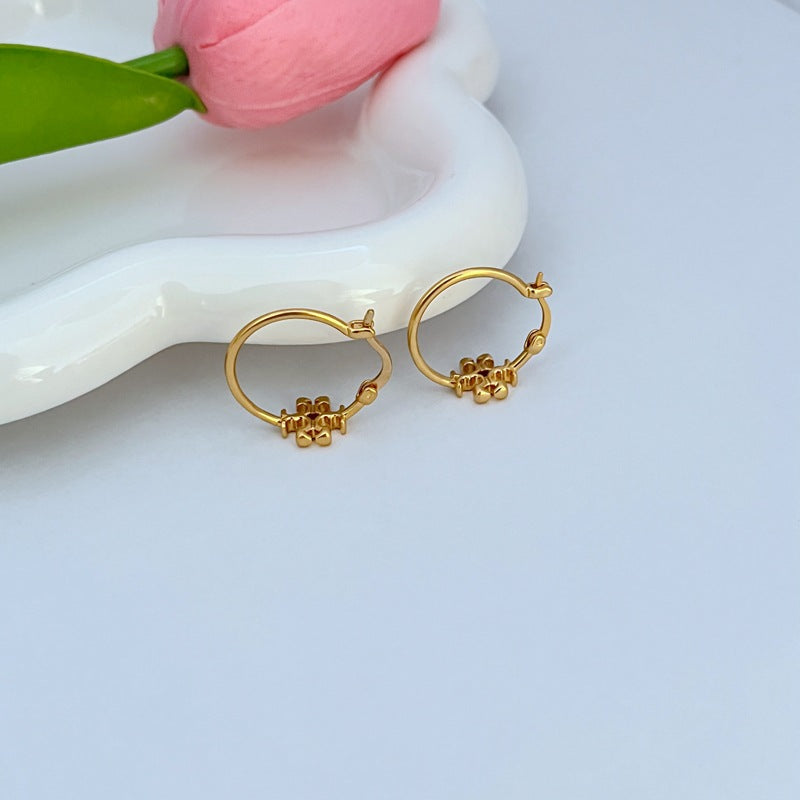 Gold-tone mini hoop earrings with logo charm, pair shown at angle